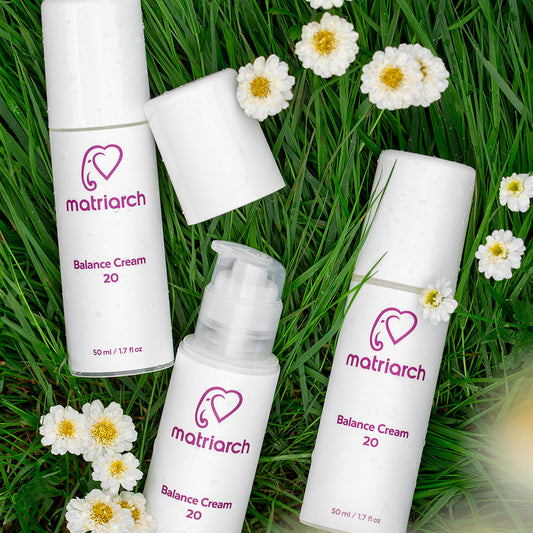 Three bottles of Matriarch Balance Cream 20 lying in green grass with small white daisies