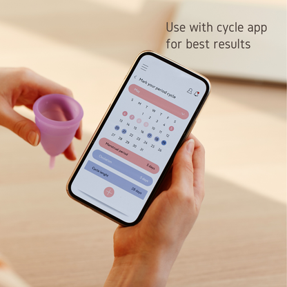 Hand holding a phone with a period tracking app and a menstrual cup, with the text "Use with cycle app for best results"